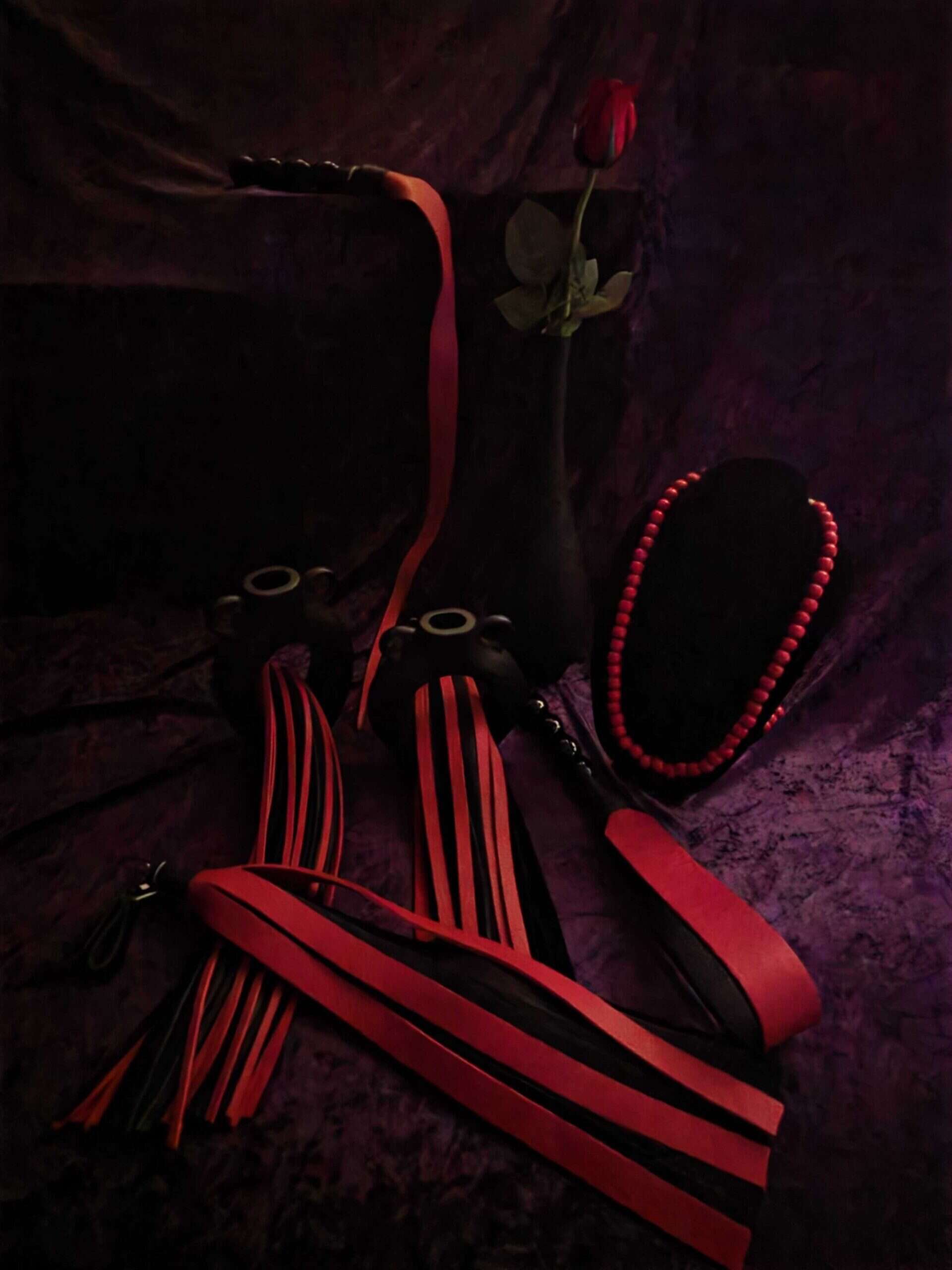 A collection of red leather floggers on a dark background