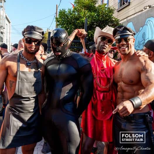 Three males in leather costumes at Folsum Street fair, posing fourth male is muscle-bound and shirtless